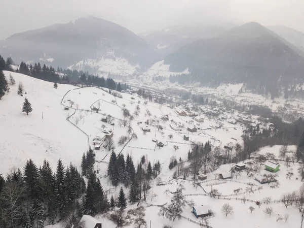 Calma e accogliente villaggio fiabesco Kryvorivnia coperto di neve nelle montagne dei Carpazi, vista aerea. Paesaggio tipico nel Parco Nazionale di Hutsulshchyna in Ucraina. Vacanze e sport invernali . — Foto Stock