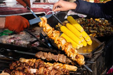 Sulu kokulu buhar parçalarıyla şiş çeviren iki el.