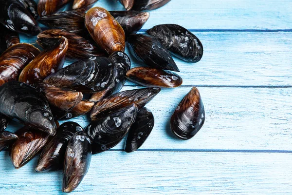 Frische rohe Miesmuscheln auf blauem Holzboden — Stockfoto