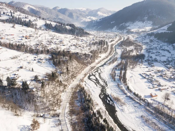 Calma y acogedor pueblo de cuento de hadas Kryvorivnia cubierto de nieve en las montañas Cárpatos, vista aérea. Paisaje típico en el Parque Nacional Hutsulshchyna en Ucrania. Vacaciones y deportes de invierno . Imágenes De Stock Sin Royalties Gratis