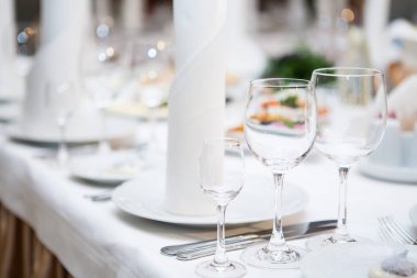 Tabaklar, aperatifler, şarap kadehleri ile servis edilen ziyafet masası.