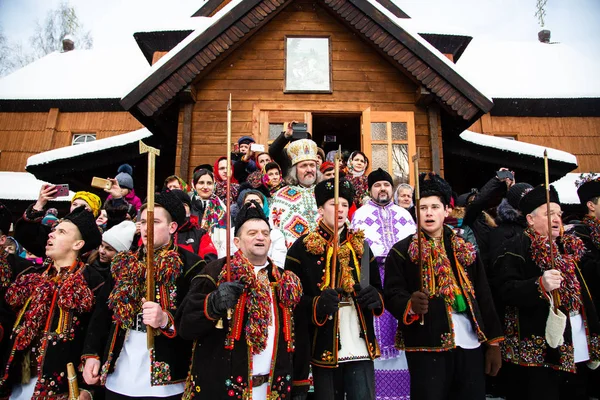 Berühmte hutsulian koliadnyky von kryvorivnia singen Weihnachtslieder und marschieren um die alte hölzerne Kirche. alte winterliche Traditionen der Karpaten. — Stockfoto