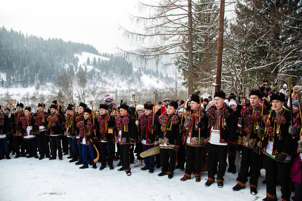 Famous hutzulian Koliadnyky of Kryvorivnia singing Christmas carols and marching around ancient wooden church. Old winter traditions of Carpathian mountains.