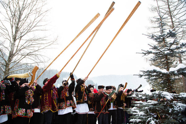 Famous hutzulian Koliadnyky in national Hutsul costume singing Christmas carols and playing on traditional trembita horn, Carpathian village Kryvorivnia