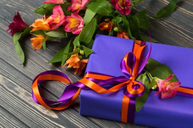 Kırmızı kurdeleli ve çiçekli mavi hediye kutusu