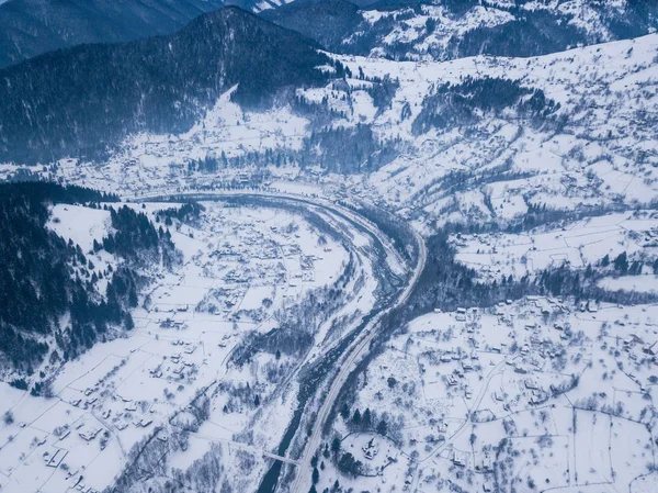 Calma y acogedor pueblo de cuento de hadas Kryvorivnia cubierto de nieve en las montañas Cárpatos, vista aérea. Paisaje típico en el Parque Nacional Hutsulshchyna en Ucrania. Vacaciones y deportes de invierno . —  Fotos de Stock