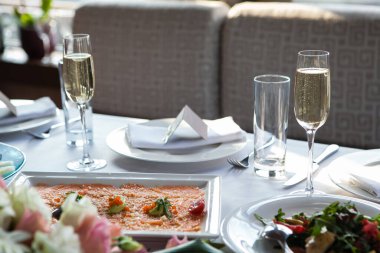 Tabaklar, atıştırmalıklar, şarap ve su bardakları ve Avrupa yemekleriyle birlikte ziyafet masasında servis ediliyor.