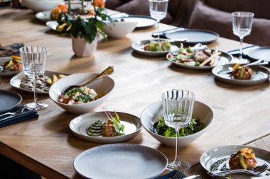 Tabaklar, atıştırmalıklar, şarap ve su bardakları ve Avrupa yemekleriyle birlikte ziyafet masasında servis ediliyor.