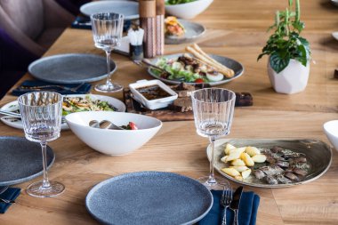 Tabaklar, atıştırmalıklar, şarap ve su bardakları ve Avrupa yemekleriyle birlikte ziyafet masasında servis ediliyor.