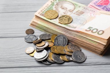 Ukrayna 'nın parası. Gri ahşap masanın üzerinde farklı küçük paralarla Ukrayna Hryvnia banknotları yığını
