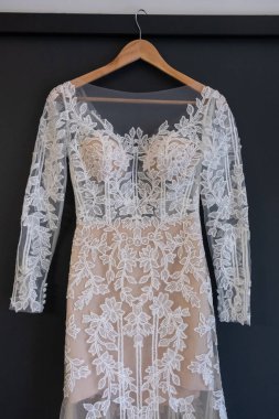 Bir askı bir pencere yakınında asılı parlak bej renkli gelinlik