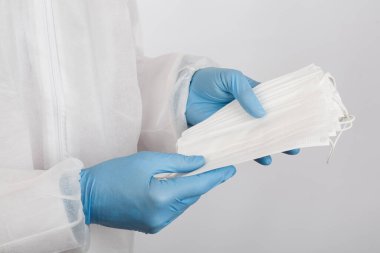 Beyaz arka plandaki enfeksiyondan korunmak için doktor elini tıbbi bir yüz maskesi ile kapat.