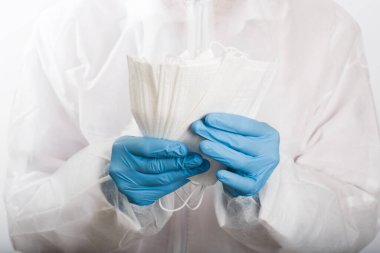 Beyaz arka plandaki enfeksiyondan korunmak için doktor elini tıbbi bir yüz maskesi ile kapat.