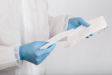 Beyaz arka plandaki enfeksiyondan korunmak için doktor elini tıbbi bir yüz maskesi ile kapat.