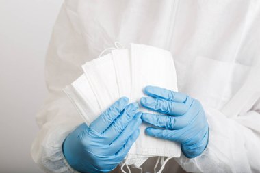 Beyaz arka plandaki enfeksiyondan korunmak için doktor elini tıbbi bir yüz maskesi ile kapat.