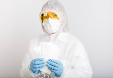 Tek kullanımlık anti-salgın takım elbiseli doktor maske takıyor ve beyaz arka planda enfeksiyon virüsüne karşı korunmak için tıbbi maske takıyor.