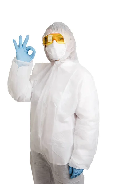 Maske ve gözlük takan tek kullanımlık anti-salgın takım elbiseli doktor beyaz arka planda izole edilmiş sembol yapıyor.