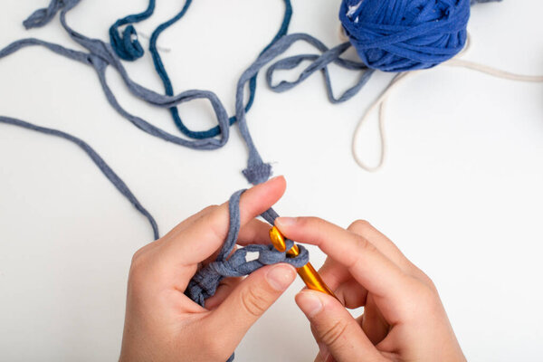 Different colored balls of yarn. Children's hands are crocheted and thread view frome above