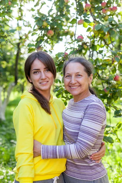 Anciana con hija adulta en huerto de manzanas . — Foto de Stock