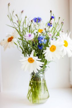 Şeffaf sürahide bir buket yabani çiçekle hayat. 