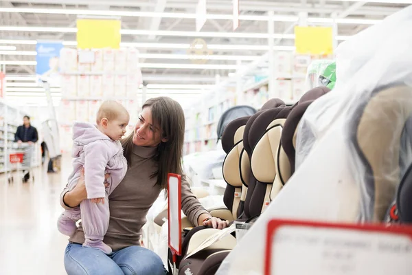 Fiatal Anya Kislányával Autóülés Kiválasztása Gyermekáruk Tárolására — Stock Fotó