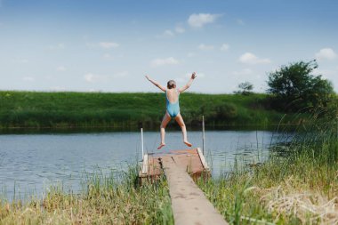  Köydeki nehir köprüsünde mayo giymiş bir çocuk.