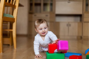 9 aylık küçük bir çocuk evin zemininde oynuyor..