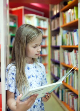   Okul kütüphanesinde kitap seçen birinci sınıf öğrencisi. 