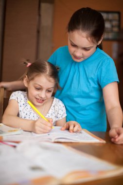 Ablam küçük kız kardeşine derslerinde yardım ediyor.