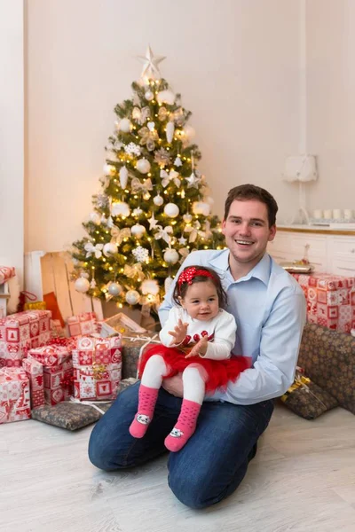 Joven familia feliz delante de un árbol de Navidad —  Fotos de Stock