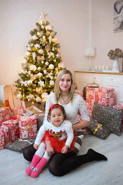 Joven familia feliz delante de un árbol de Navidad —  Fotos de Stock