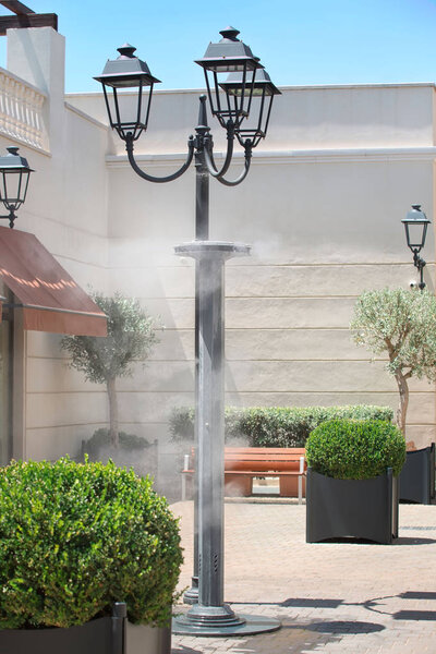 Sprinklers splashing vaporized water at street in order to cool the hot summer temperature