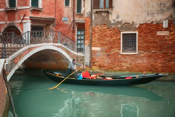 Gondoliere sulla sua gondola sotto il ponte, navigare attraverso il canale di Venezia, Italia — Foto Stock