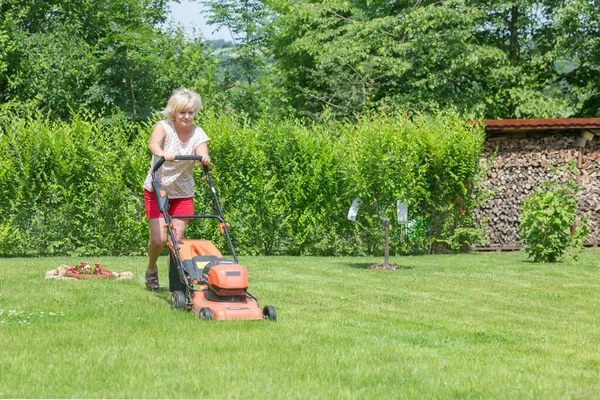 Kvinnan klipper gräset i trädgården — Stockfoto