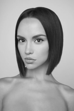 Kısa saçlı güzel esmerin sanat stüdyosu portresi. Beyaz stüdyoda çıplak vücutlu genç ve seksi bir model. Klasik profesyonel makyajlı çıplak kadın. 