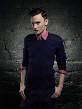 Duvara dayanmış yakışıklı ve şık bir adamın portresi. Genç bir adamın moda portresi. Modern saç stili olan çocuk..