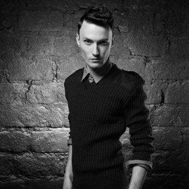 Duvara dayanmış yakışıklı ve şık bir adamın portresi. Genç bir adamın moda portresi. Modern saç stili olan çocuk..