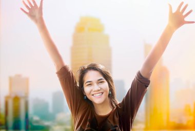 Mutlu biracial genç kız silah kaldırdı, arka planda skyscapers