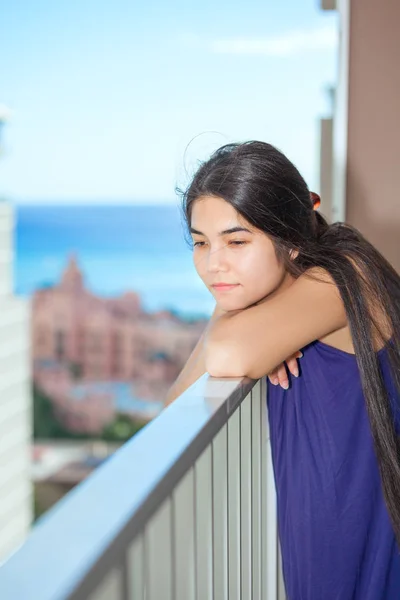 Sad biracial teen girl on outdoor highrise patio, ocean  backgro — Stock Photo, Image