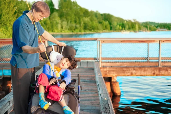 Fader att hjälpa funktionshindrade tio år gamla son i rullstol fisk — Stockfoto