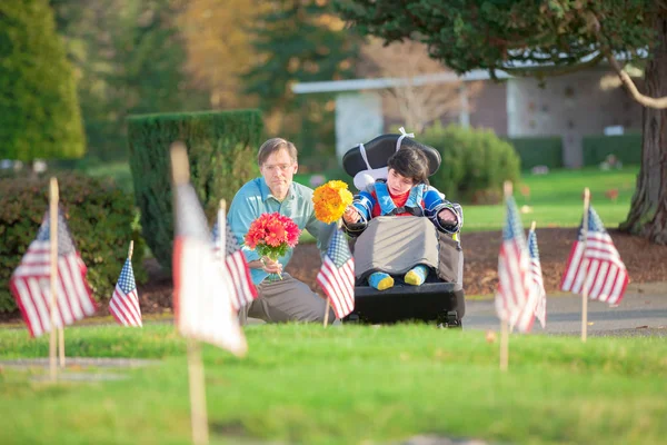 Père et fils handicapés en fauteuil roulant visitant la tombe au cimetière — Photo