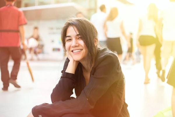 Biracial Teen Mädchen sitzen vom Bürgersteig, Passanten in backgr — Stockfoto