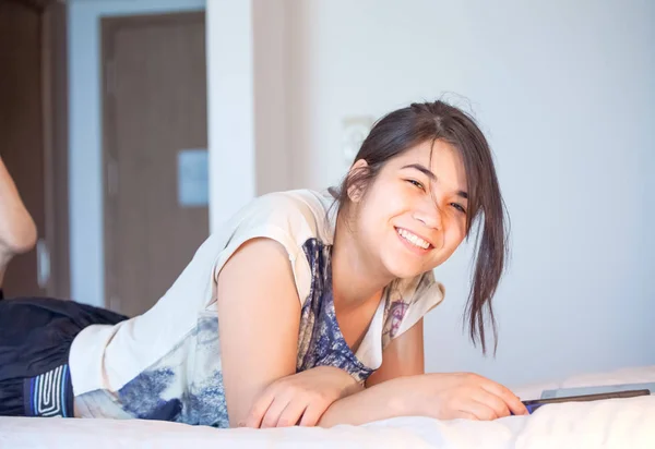 Teenie-Mädchen liegt lächelnd auf Bett und benutzt Tablet-Computer — Stockfoto