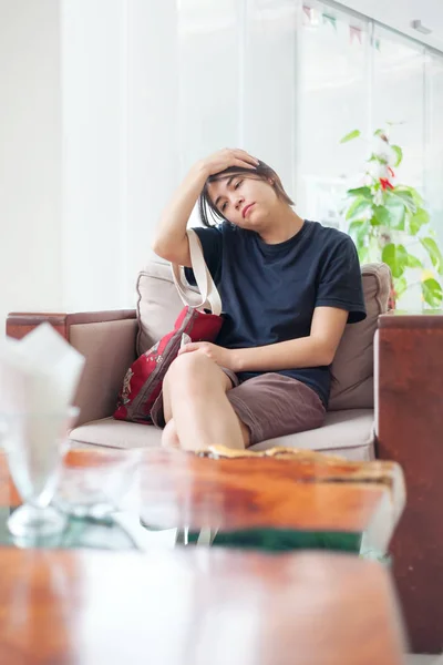 Teen girl sitting in hotel lobby with neckache or heachache — Stock Photo, Image
