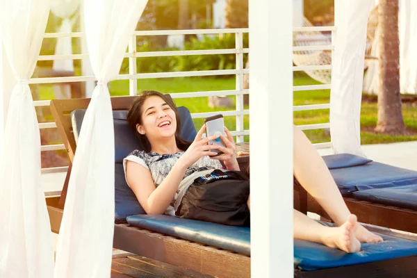 Девочка-подросток с помощью смартфона во время отдыха на шезлонге на курорте — стоковое фото