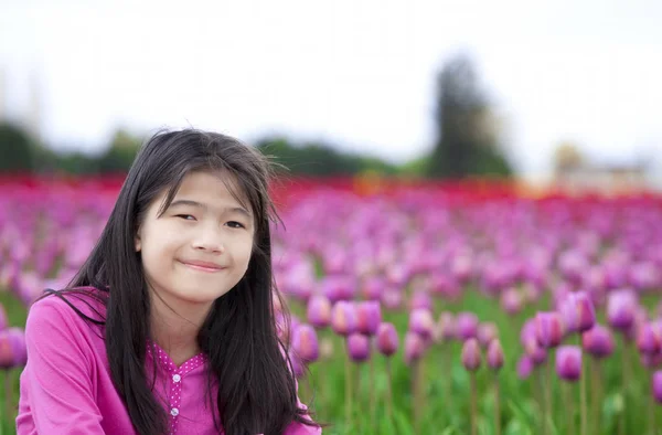 Jeune fille de dix ans souriant devant les champs de tulipes — Photo