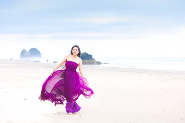 Junge Frau in fließendem magenta Kleid steht am Strand — Stockfoto