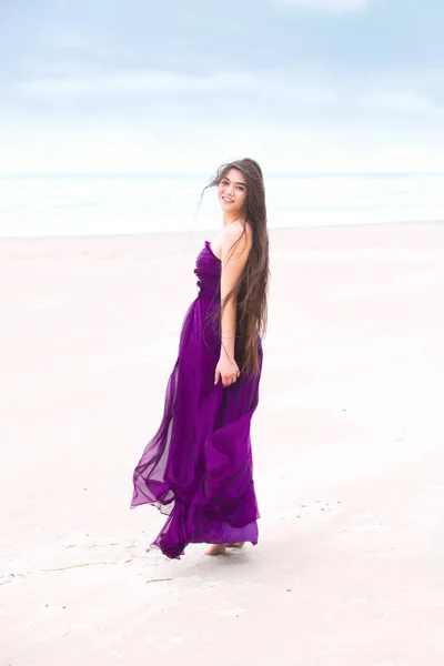Підліток у фіолетовій сукні на пляжі дивиться назад через плече — стокове фото