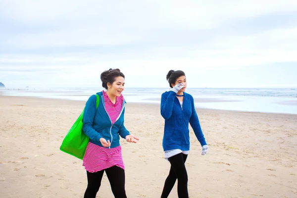 Two teenager girls walking on beach on cool cloudy day — Stock Photo, Image