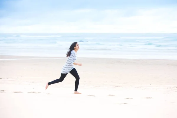 Νεαρό κορίτσι τρέχει στην παραλία από ωκεανό — Φωτογραφία Αρχείου